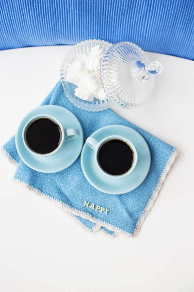 Two blue coffee cups on blue napkin saucer Marshmallow.