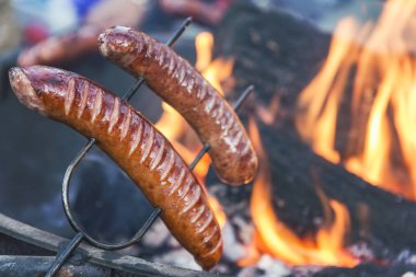 Kamp ateşi üzerinde sosis hazırlanıyor