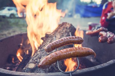 Kamp ateşi üzerinde sosis hazırlanıyor