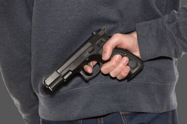 Koyu mavi kot pantolon ve kapüşonlu giyen tabanca tutan silahlı kişi