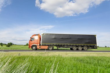 Yolda giden nakliye kamyonu, mavi gökyüzü olan yeşil çayır.