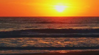 Okyanus ufkunun üzerinde altın gün batımı, plajda sıcak bir yaz akşamı