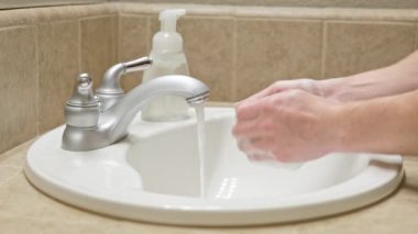 Banyo lavabosunda sabun ve suyla ellerini yıka