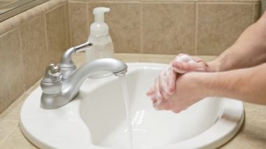Banyo lavabosunda sabun ve suyla ellerini yıka