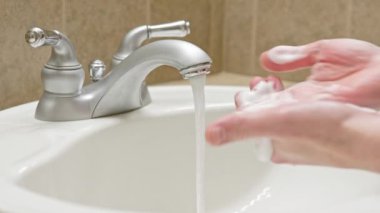 Banyo lavabosunda sabun ve suyla ellerini yıka