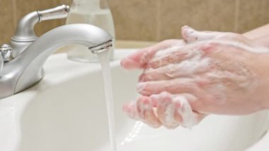 Banyo lavabosunda sabun ve suyla ellerini yıka
