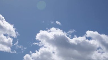 Yavaş kamera hareketi, güneşli mavi gökyüzünde beyaz bulutlar, parlayan mercek, güneşe bakıyor, 4k