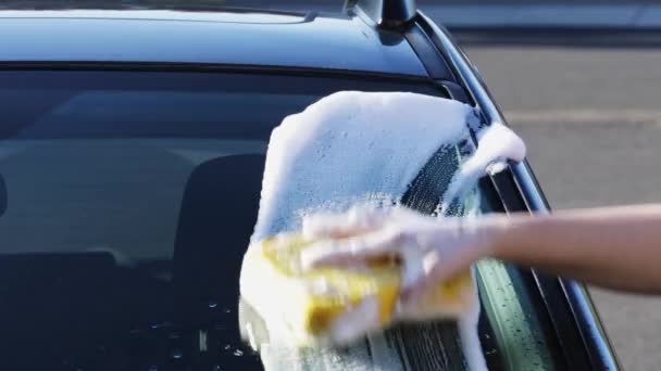 用海绵和洗发水洗车 用手将泡沫撒在湿透的深色汽车上 — 图库视频影像