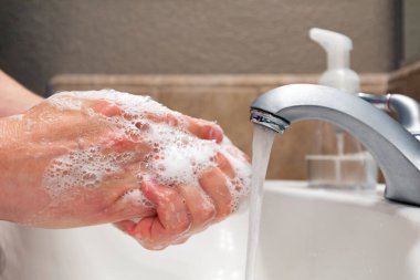 Banyo lavabosunda sabun ve suyla ellerini yıkamak, virüslere ve bakterilere karşı koruma, sağlıklı kalmak için hijyen.