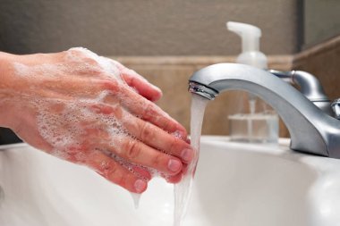 Banyo lavabosunda sabun ve suyla ellerini yıkamak, virüslere ve bakterilere karşı koruma, sağlıklı kalmak için hijyen.