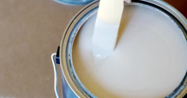 Konteynırda tahta bir sopayla el yapımı beyaz boya, yakın plan yeni boya konservesi, 4K