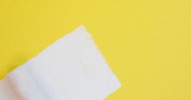 El silindiri ile boyama, sarı duvarın üzerine beyaz boya yakın plan, oda yenilenmesi, 4K 