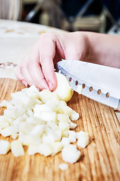 Womans hand with a knife cutting the boiling potatoes — Stock Photo, Image