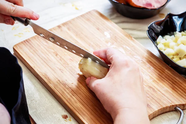 Женская рука с ножом режет кипящий картофель — стоковое фото