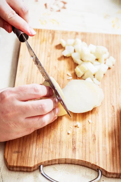 Womans hand with a knife cutting the boiling potatoes — Stock Photo, Image