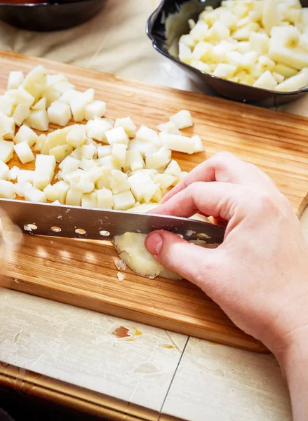 Womans hand with a knife cutting the boiling potatoes — Stock Photo, Image