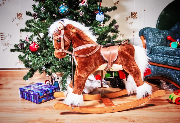 Детская лошадка на фоне рождественской елки — стоковое фото