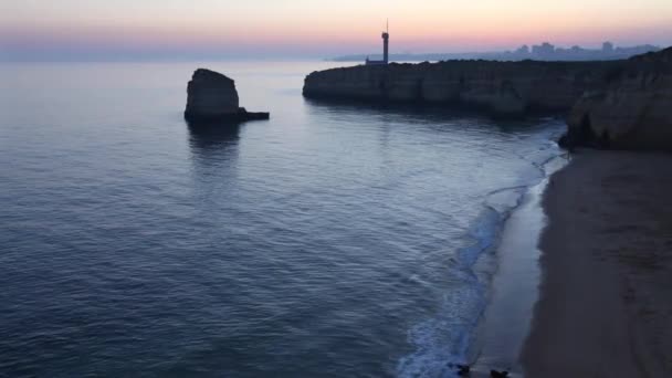 Deniz kıyısında günbatımı manzara ve deniz feneri. — Stok video