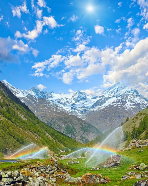 Arcobaleni in bocca d'acqua di irrigazione in montagna Alpi estive — Foto Stock