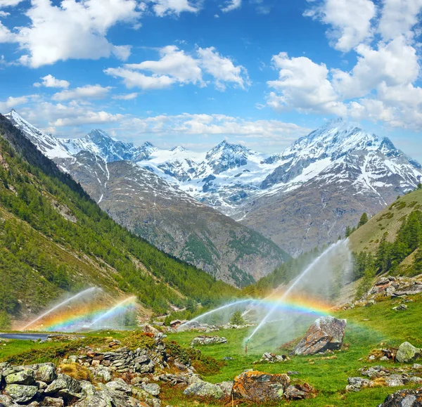 Rainbows in irrigation water spouts in Summer Alps mountain