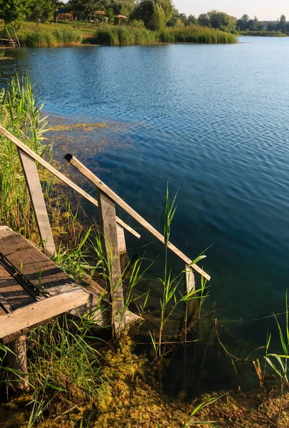 Verão lago calma praia com madeira íngremes para a água — Fotografia de Stock
