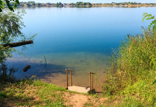 Latem jezioro spokojny plaży z drewna steeps do wody — Zdjęcie stockowe