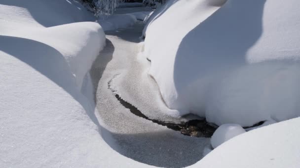 小山溪流 雪岸上飘扬的大雪 冷水平静流动和冰水表面 — 图库视频影像