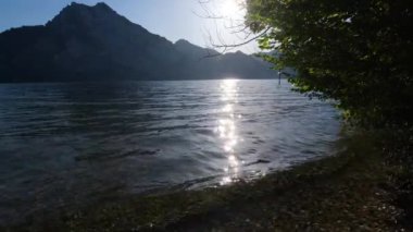 Traunsee Gölü ve Yukarı Avusturya 'daki Traunstein Dağı' na huzurlu bir sonbahar sabahı manzarası. Güneş ışığı su yüzeyinde yanıp sönüyor..