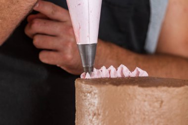 Bir şefin ellerini çikolatalı geyiğin üstüne çilekli geyik süsleyerek bir doğum günü pastasını süslüyordu.