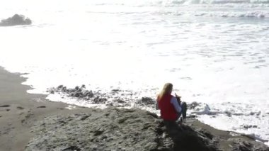Oregon sahilindeki dalgaların gelgitlerle hareket edişini izleyen bir kadın.