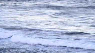 Oregon sahilinde güneşli bir günde plaja girip çıkan dingin dalgalar.