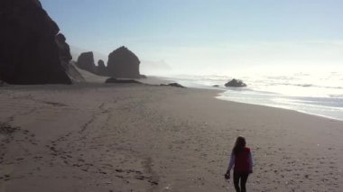 Kumsalda gezen bir kadın hazine ve cilalanmış taşlar arıyor ve Gold Beach Oregon 'da her zaman popüler olan