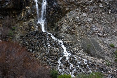 Kuzey Kaliforniya 'daki dağlarda mevsimlik bir şelale manzarası kayalık bir yamaçtan aşağı dökülüyor.