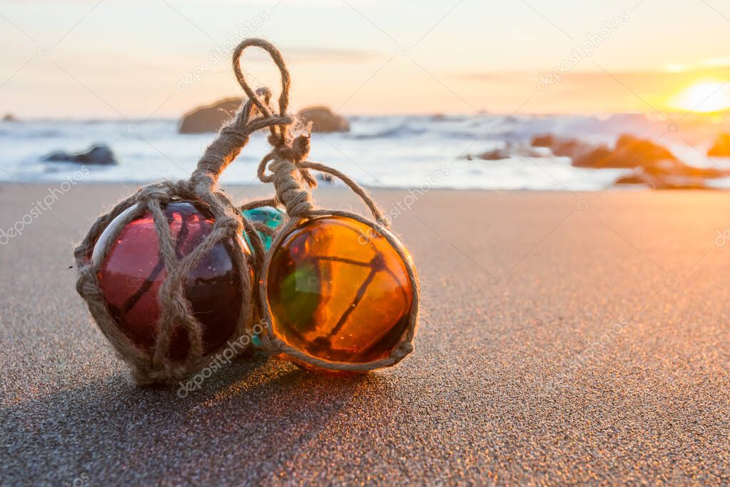 sunset in the Oregon coast with colorful glass floats on a a sandy beach