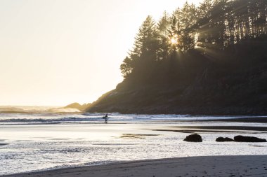 Hunterlarda sörf yapanlar, arka planda gün batımıyla örtüşürler. Rüzgara bir parıltı eklerler. Dalgaların tepesinden fışkıran bir sprey.