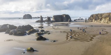 Bandon by the Sea, Oregon / USA - 07 Mart 2020: The team of Circles in the Sand Face Rock State Park 'ın düz kumlu plajında yürünebilir bir labirent çiziyor