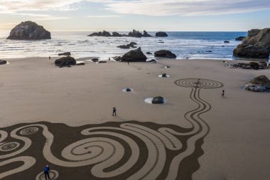 Bandon by the Sea, Oregon / USA - 08 Mart 2020: Team of Circles in the Sand Face Rock State Park plajında yürünebilir bir labirent çiziyor