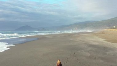 Oregon 'un güneyindeki güzel Nesika Sahili' nde küçük bir köpeği gezdiren kadın.. 