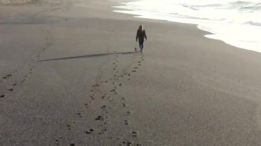 Oregon 'un güneyindeki güzel Nesika Sahili' nde küçük bir köpeği gezdiren kadın.. 