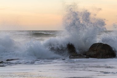 Nesika Sahili, Oregon 'daki Rocky kıyı şeridi. Öğleden sonra güneş ufka yaklaşırken dalgalar kayalara çarpıyor.