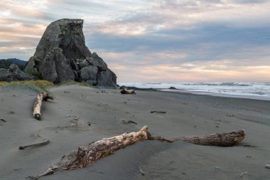 Güneş ufukta batarken güzel bir manzara kara bulutlara renk ve Oregon sahilinde bulunan kum ve otlara biraz ışık katıyor..