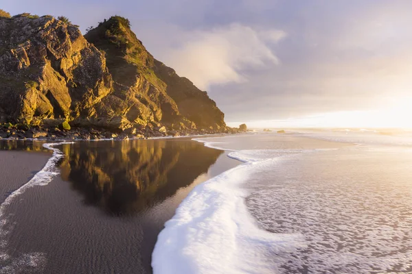 Güneş ufkun altına batarken Güney Oregon sahillerindeki manzaraya parlaklık ve renk katarken, altın ışık Cape Sebastian 'daki kayalara yansıyor.