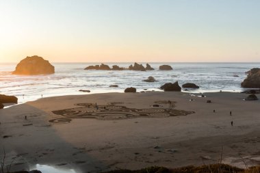 Bandon by the Sea, Oregon / USA - 20 Şubat 2020: Face Rock State Park 'ın düz kumlu plajında Circles in the Sand ekibi tarafından yapılan labirentte yürüyen insanlar