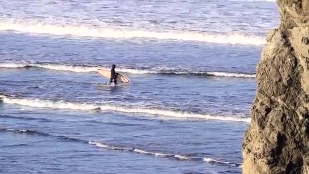 美国俄勒冈州班顿 2020年3月13日 身穿全套干衣的男子带着冲浪板走出海洋 — 图库视频影像