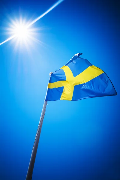 Sweden flag against blue sky in bright sunshine — ストック写真