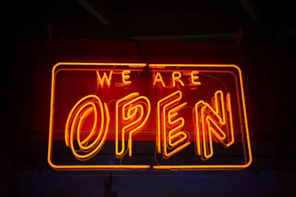 Sinal de néon aberto contra fundo escuro mostrando aberto para negócios — Fotografia de Stock