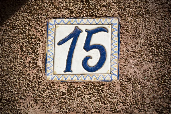 Número quinze número de porta esmaltada na parede de gesso — Fotografia de Stock
