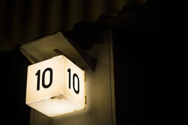 Negrito número dez sinal brilhando contra grande fundo escuro — Fotografia de Stock