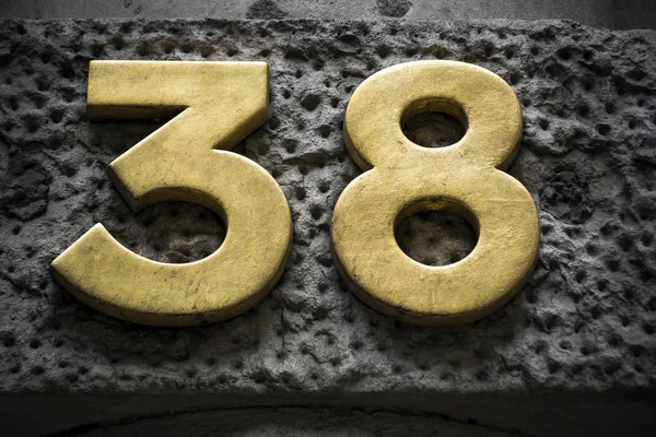 Gyllene nummer trettioåtta på mörk vägg — Stockfoto