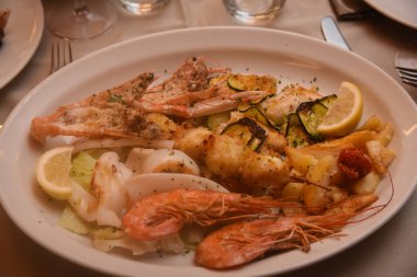 Beyaz tabakta sebze ile çeşitli lezzetli ızgara deniz ürünleri .